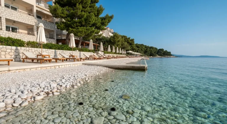 Kamienista plaża hotelowa w Makarskiej z leżakami, pomostem i wejściem do Adriatyku