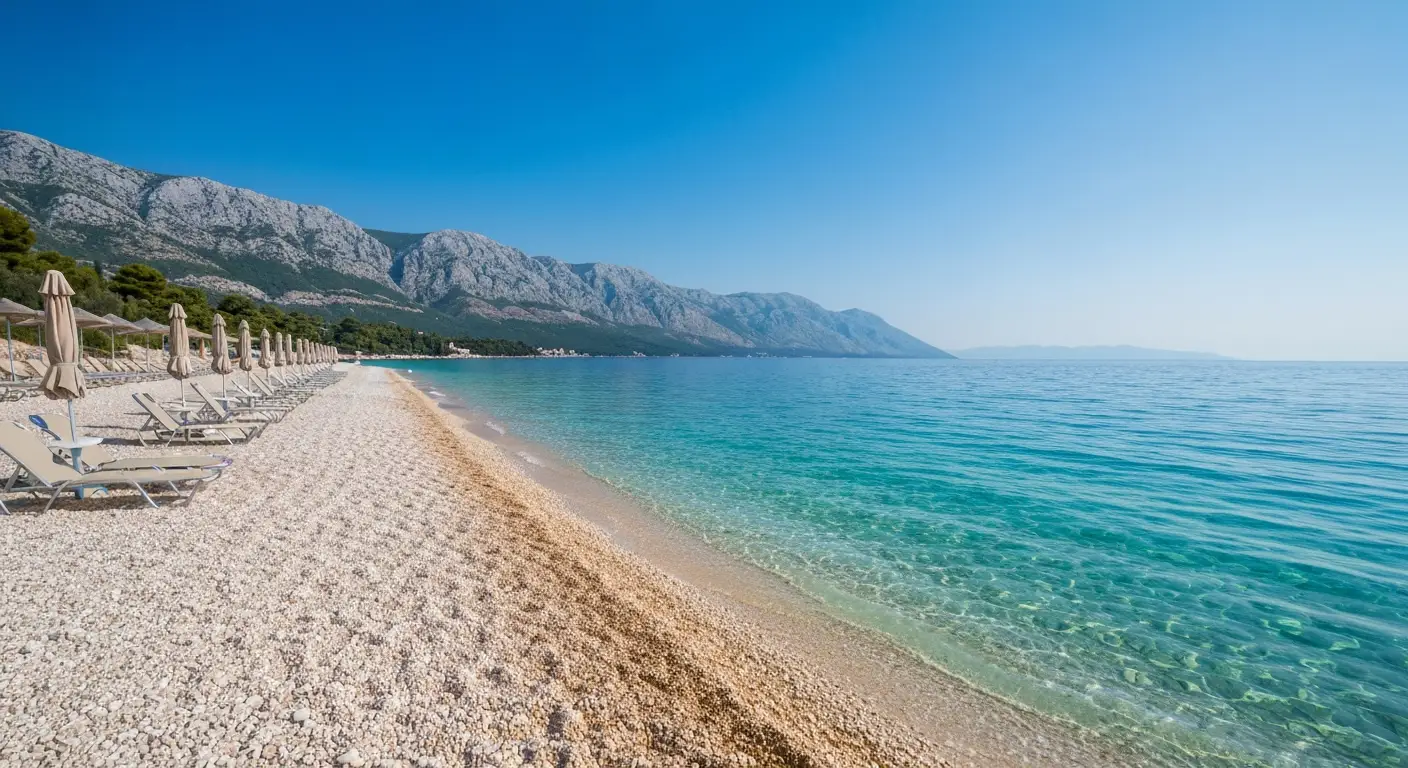 Spokojna kamienista plaża koło Makarskiej w czerwcu z turkusowym Adriatykiem i górami Biokovo