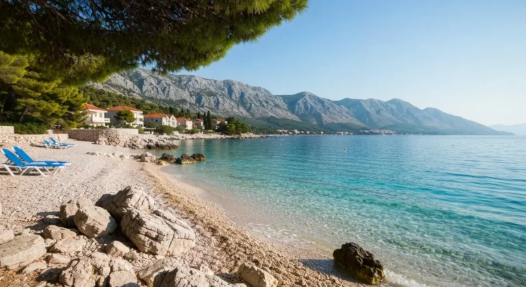 Spokojna kamienista plaża na Riwierze Makarskiej z ciepłym Adriatykiem i górami Biokovo