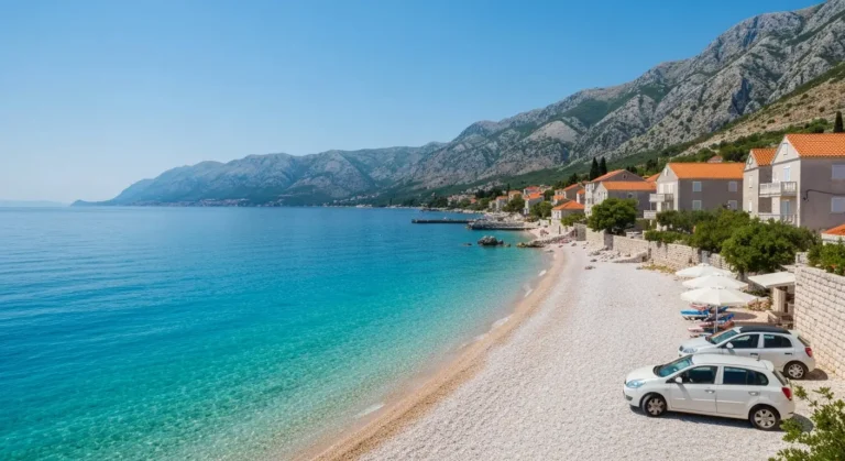 Kamienista plaża nad Adriatykiem z wapiennymi górami i dalmatyńską zabudową